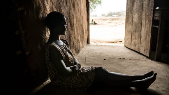 A Uganda woman with a physical disability sits alone in her house.
