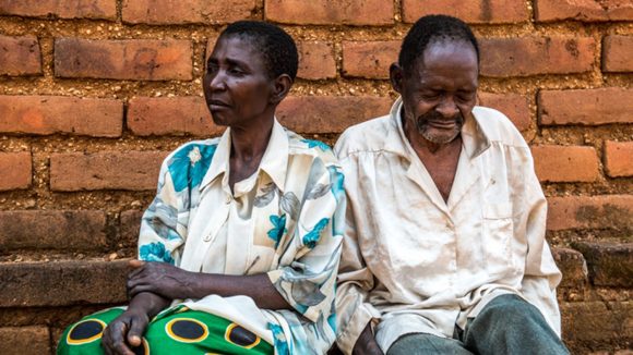 Winesi, who has cataracts, sits outside his home in Malawi with his wife Namaleta.