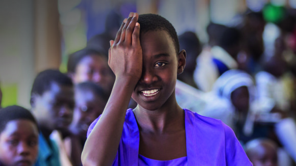 A child is holding one hand across one eye during a screening for eye diseases at Soroti hospital in Uganda as part of the Seeing is Believing project.
