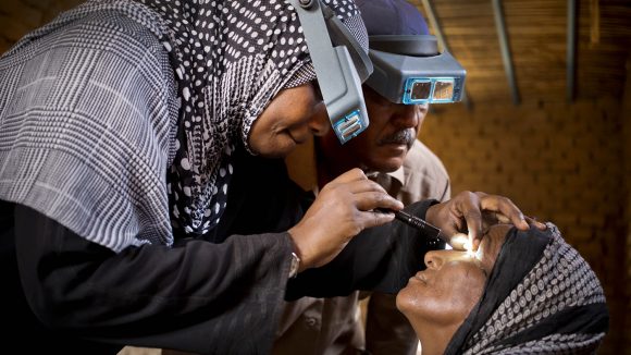 An eye health worker examines a woman's eyes for signs of trachoma.