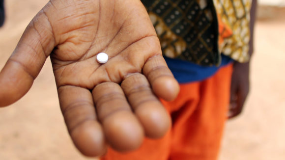 A boy holds a tablet used to treat neglected tropical diseases.