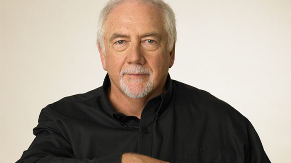 Portrait of Brien in black shirt against white background.
