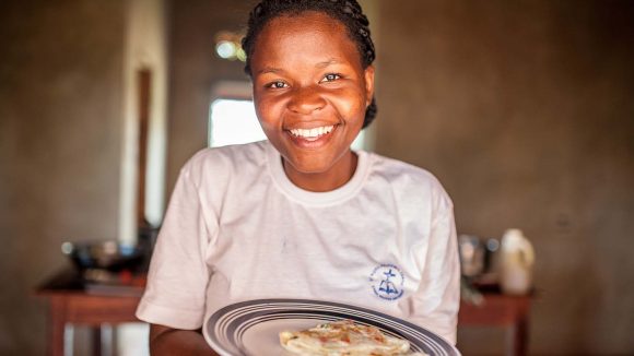 Women smiling at camera, holding plate with omelette