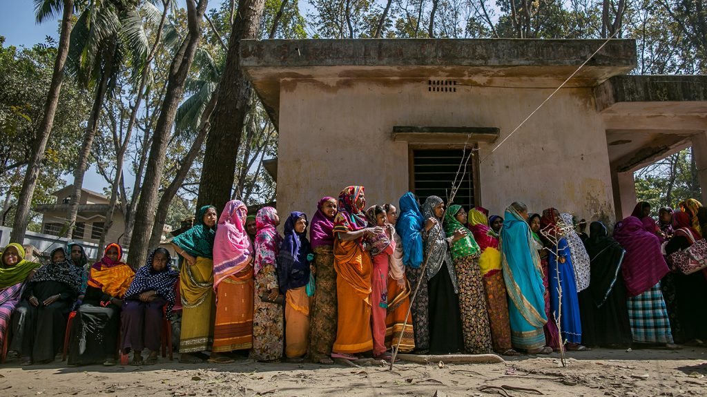 Women wearing bright colours, queue for an eye health screening in Bangladesh.