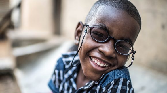 Sadhi, a young boy, wearing glasses and smiling