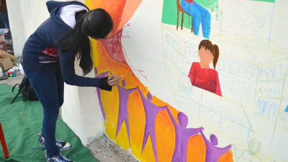 Art student painting the Inclusive Eye Health mural in Bhopal.