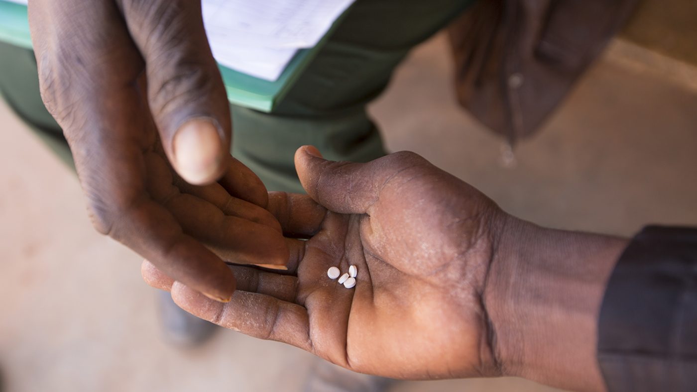 A photo of two hands. In one hand there are three tablets.
