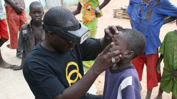 A boyhas his eyes examined by a health worker in Senegal.