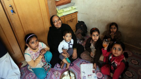In Pakistan, a disabled mother sits with her large family.