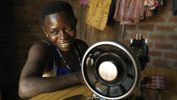 A Ugandan woman sewing clothes.