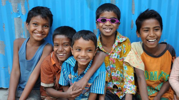 A group of smiling children in Bangladesh, some wearing spectacles.