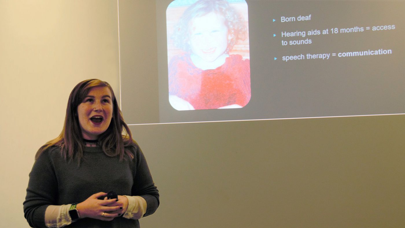 Molly Watt stands in front of the projector during her presentation at Sightsavers.