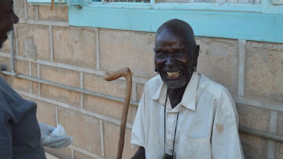 A man sitting outside with a huge smile.
