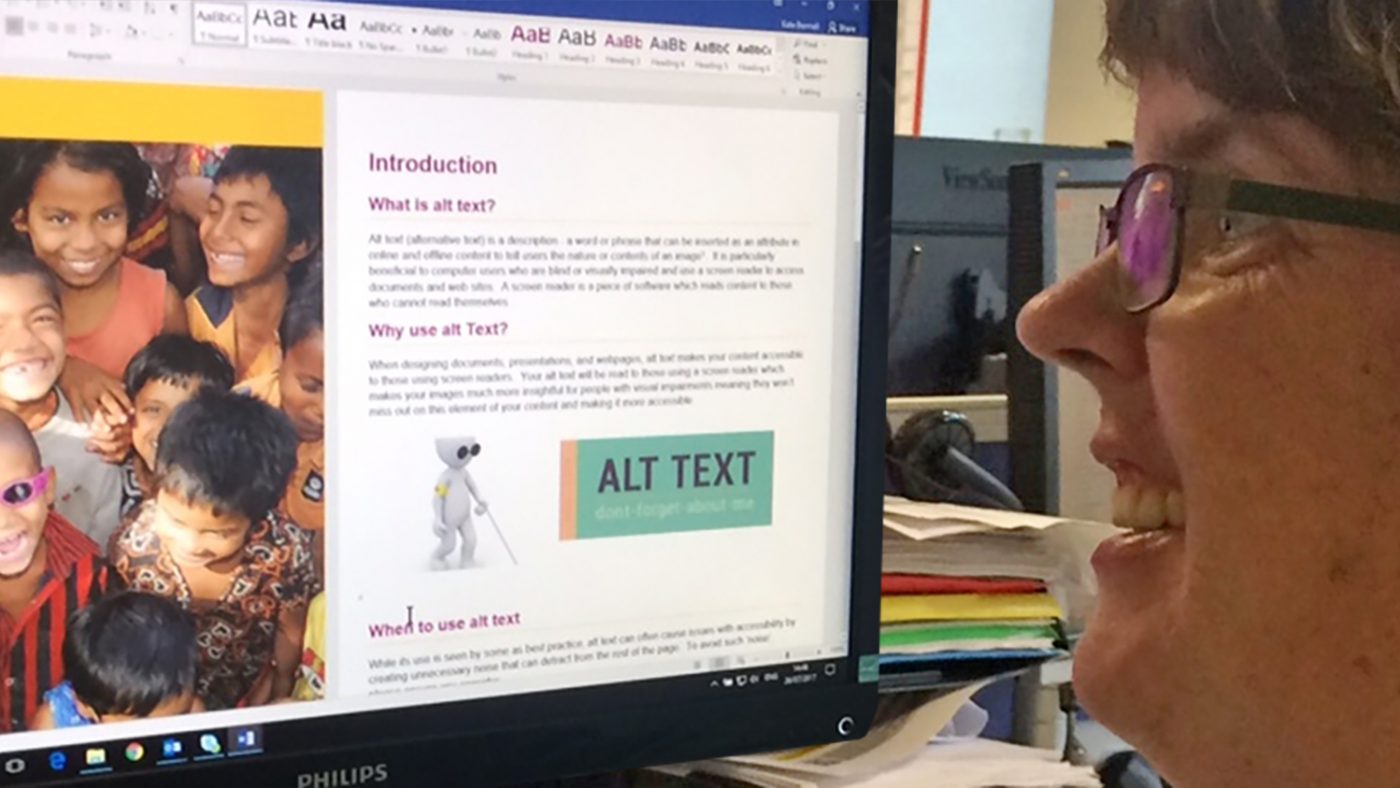 Sightsavers Social Inclusion Coordinator Kate Bennell sits at her computer, looking at a document on screen about alt text.