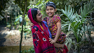 A women in Bangladesh holds her daughter in her arms, both are very happy.