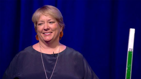 Caroline Harper, CEO of Sightsavers, holding a dose pole.