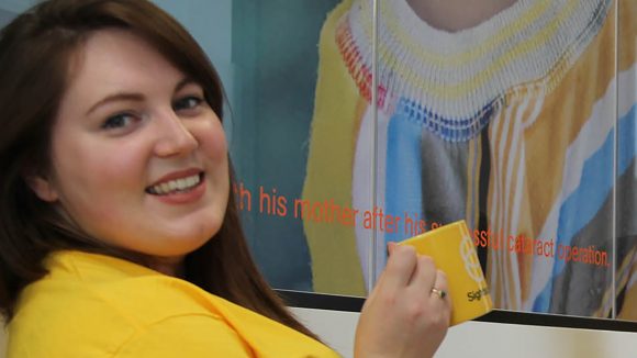 Charlotte from our Supporter Care team smiles while wearing a yellow Sightsavers T-shirt.