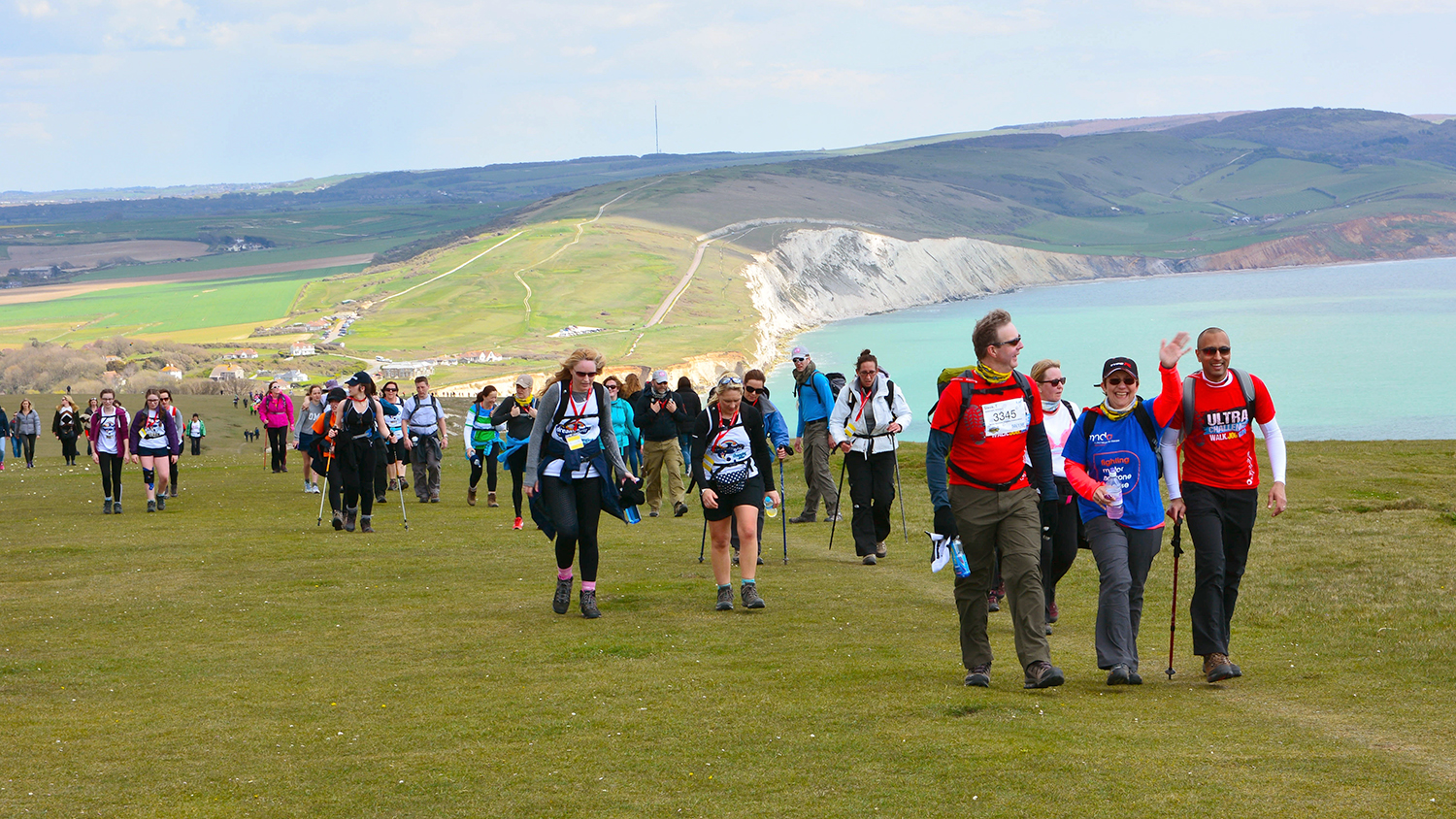 A group of hikers walk across spectacular clifftop scenery.