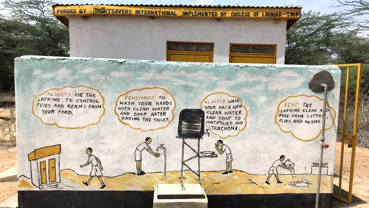 A painted wall outside a toilet block, instructing children to wash their hands.