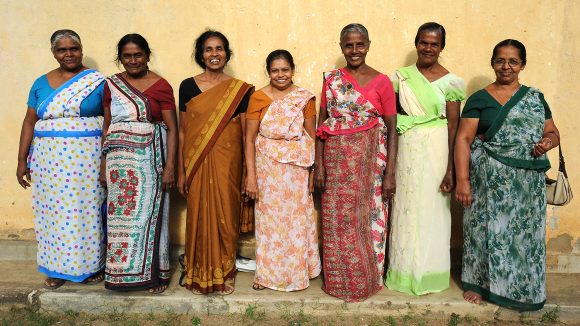 Seven women in a line are smiling.