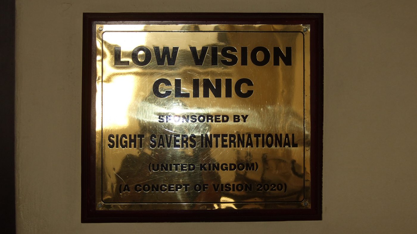 A sign saying 'Low vision clinic, sponsored by Sightsavers international.