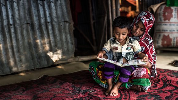 Four-year-old Arman sits on his mother's lap while they read a book.