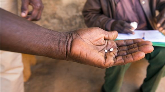 A close-up of a man's hand holding two tablets.