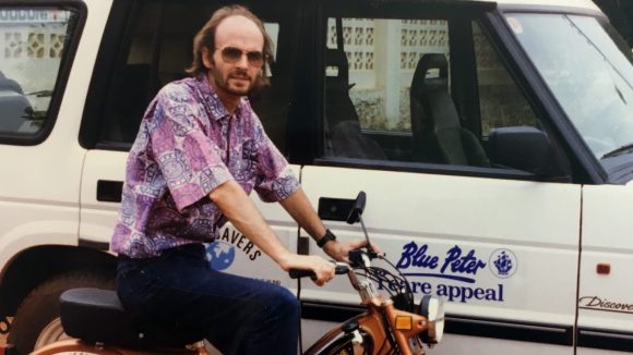 A man on a motorbike next to a truck with a logo that says 'Blue Peter Sight Savers Appeal'.