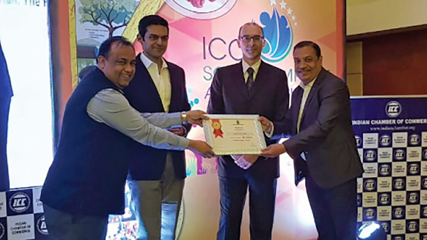 Four people smile while holding a certificate.
