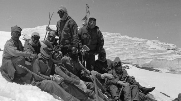 Old black and white photo showing a group of young men on a mountain slope.