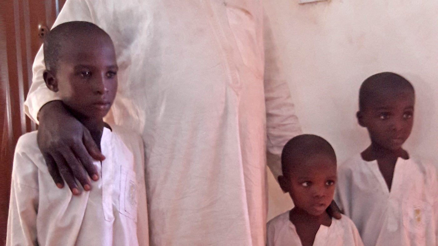 Three young boys wearing white smocks.