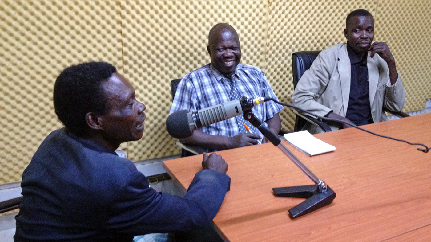 A man speaks into a microphone at a radio studio in Uganda.
