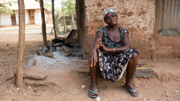 A woman affected by lymphatic filariasis (LF) sits outside her home.