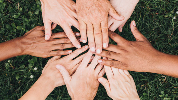 A close-up of people placing their hands on top of one another.