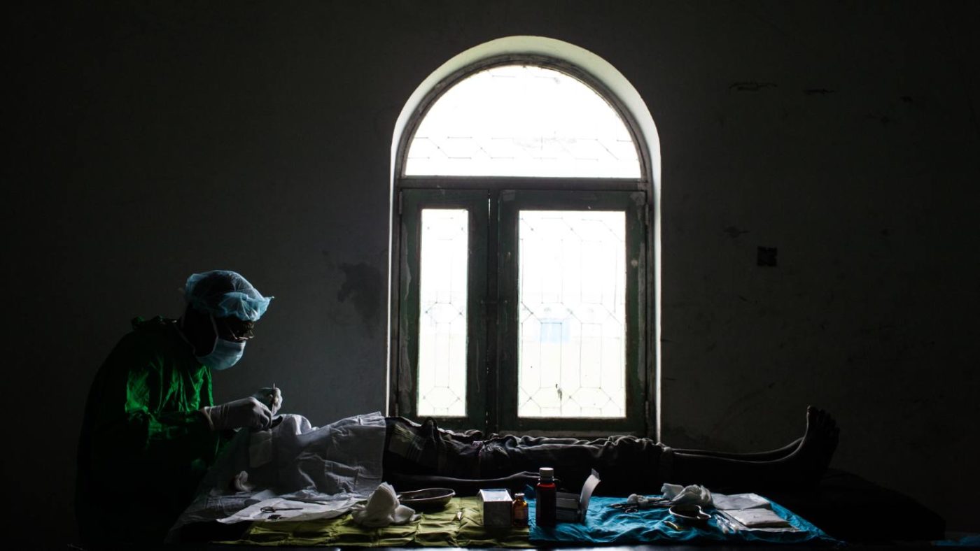 A surgeon operates, using only the light of a window, on a patient to save their sight from trachoma.