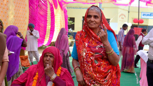 Two women hold up their index fingers after voting in the 2019 Indian general election.