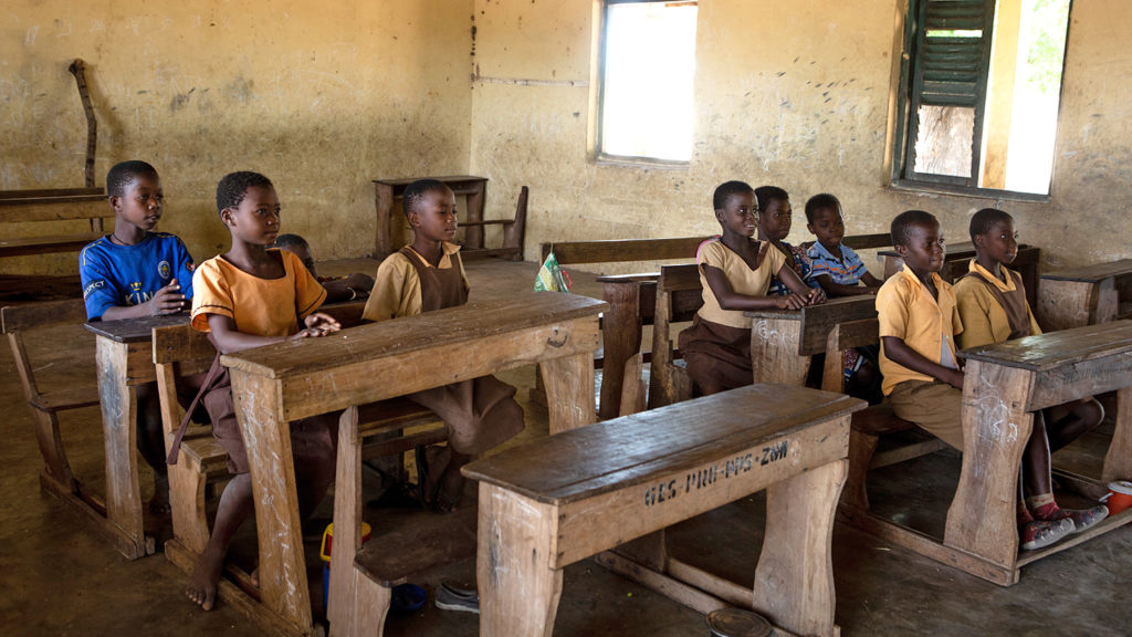 Students sit at wooden desks in their classroom in Asubende.