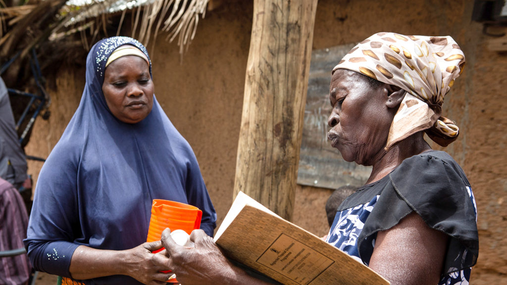 Mary holds paperwork while chatting to a patient.