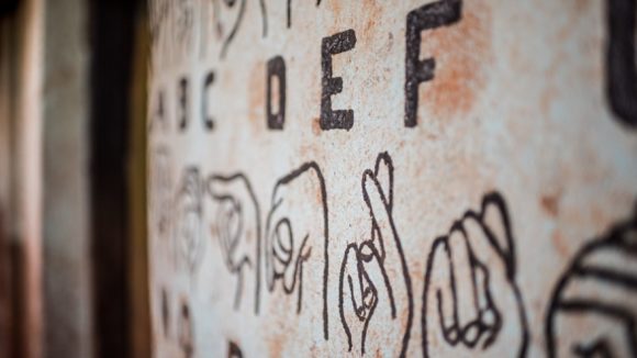 Picture of a sign language chart painted onto a school wall in Uganda.