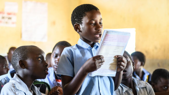 Gladys reading out loud to her classmates at school