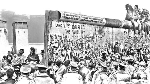 A historic photo of people gathering at the Berlin Wall.