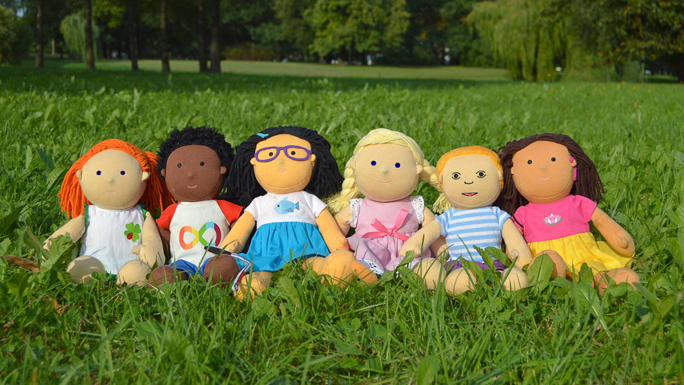 Six children's dolls lined up in a field