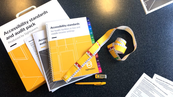 The contents of the accessibility audit pack spread on a table, including the accessibility standards, checklist, a tape measure, pen and USB stick.