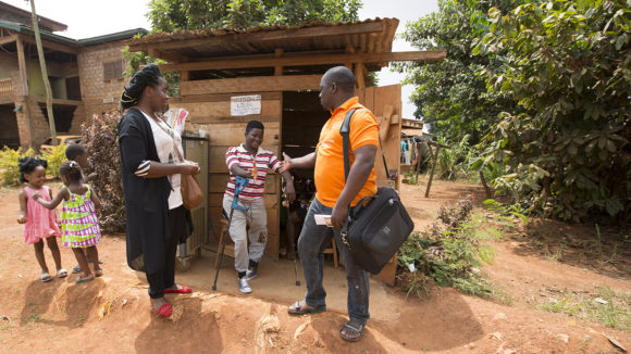 Someone on crutches shakes a man's hand.