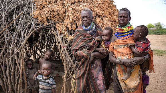 Two women and five small children stand outside their home.