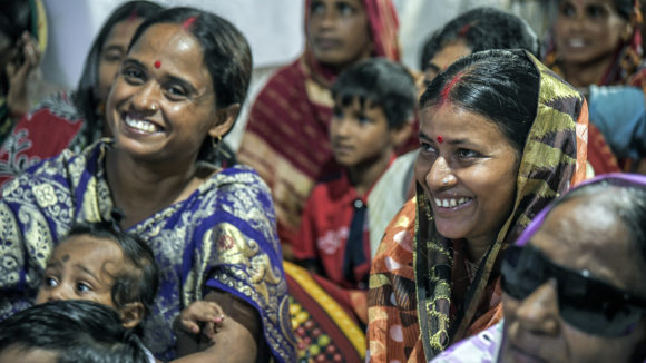 Women in an audience of a puppet show laughing.