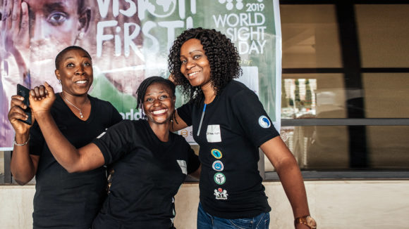 Three women posing together with smiles.
