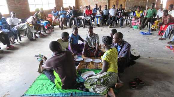 Adults sit on the floor together.
