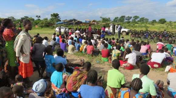 Many people sit outside on the ground in Malawi.