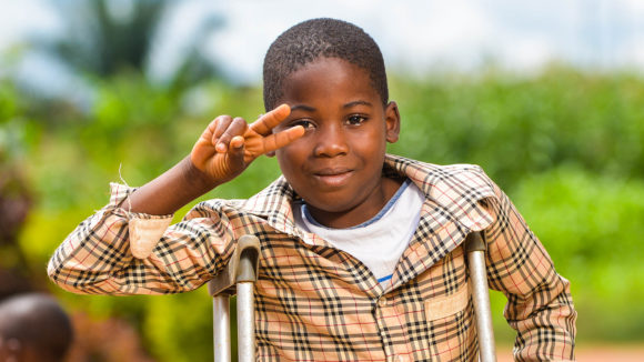 Zambo makes a V for Victory sign with his fingers at school in Cameroon.